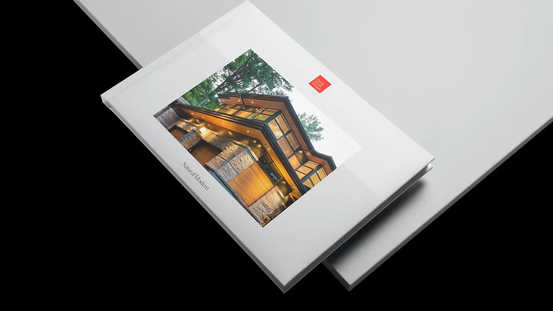 Hardcover book design featuring a modern timber-and-glass home at dusk