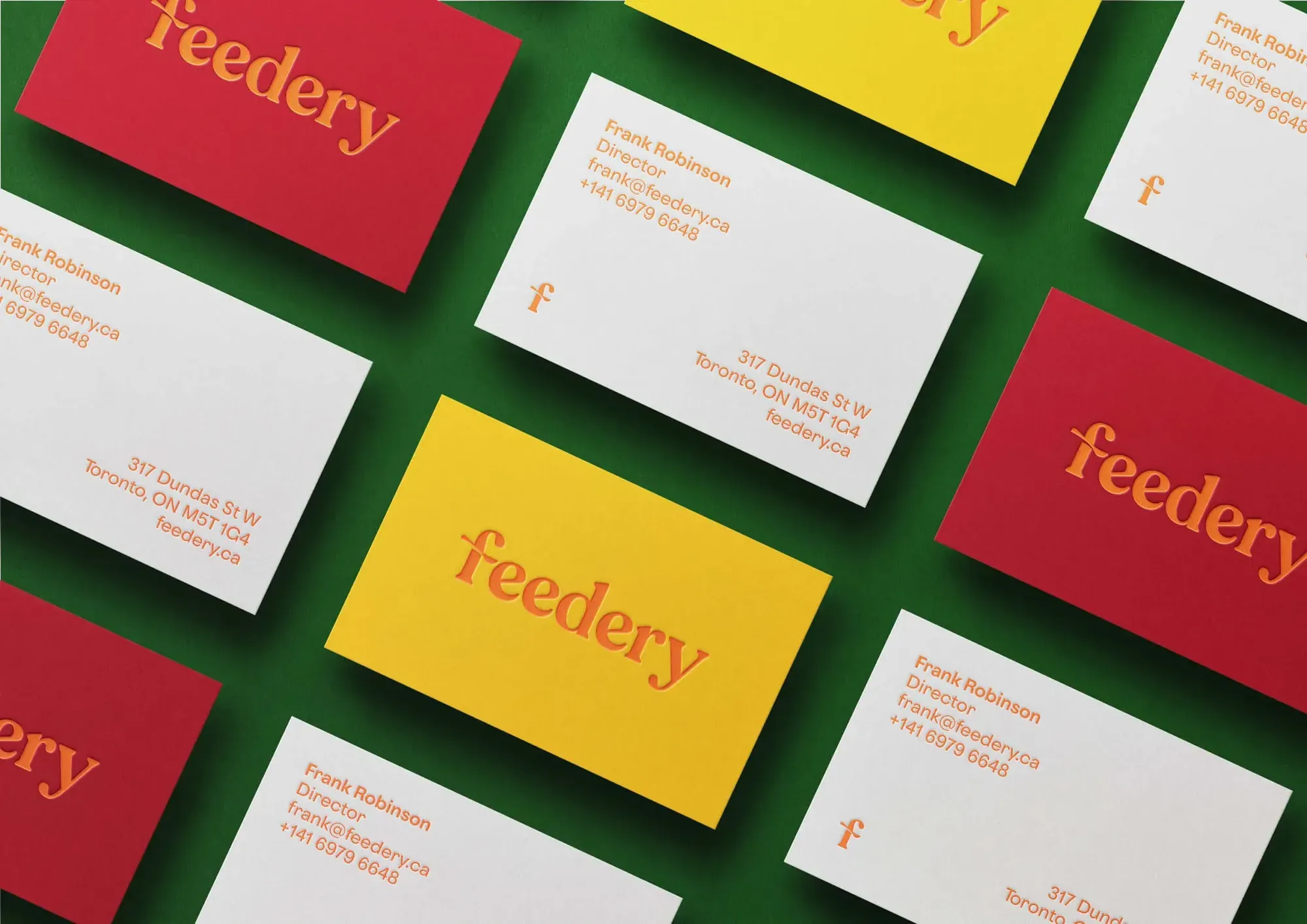 Feedery business cards in red, yellow and white laid out on a green background