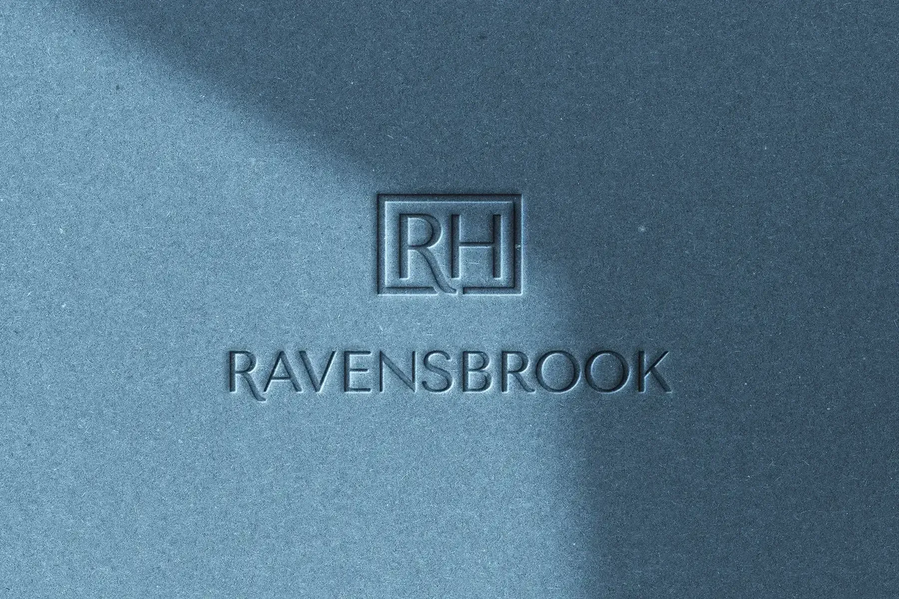 Ravensbrook RH monogram and wordmark embossed into blue textured paper