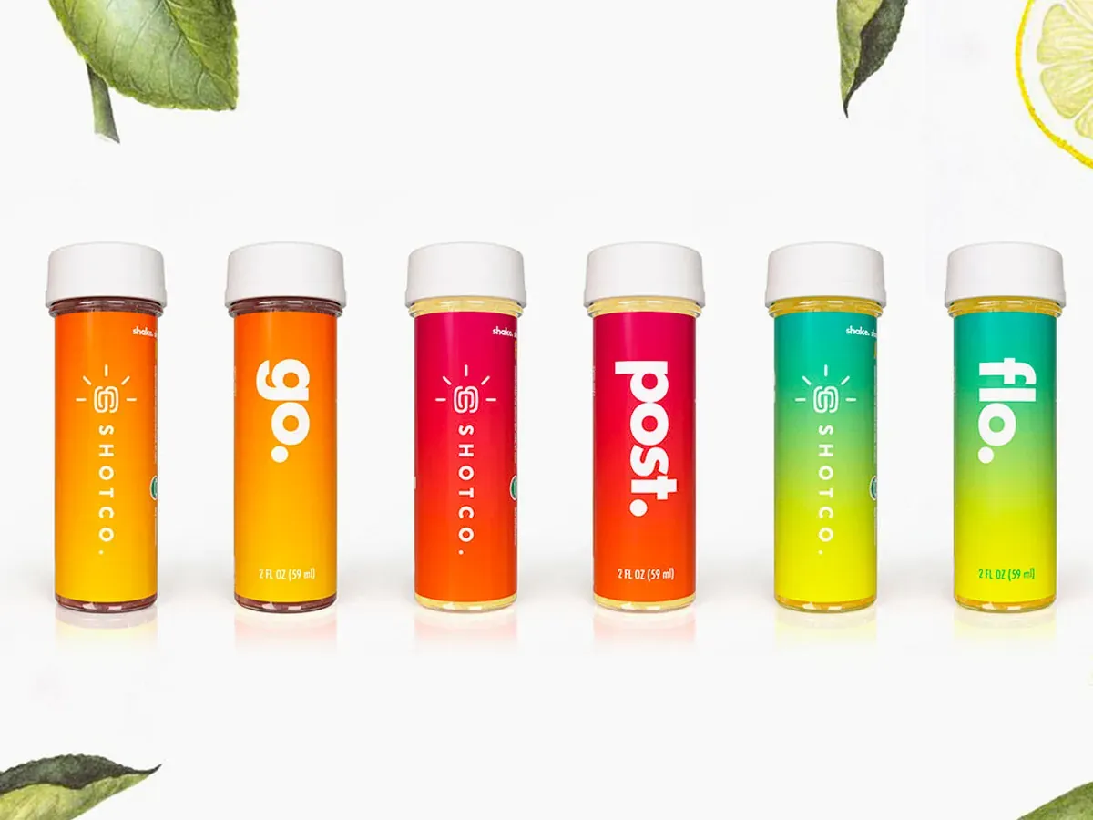 Row of six Shotco juice shot bottles in orange, red, pink and green, labelled go, post and flo