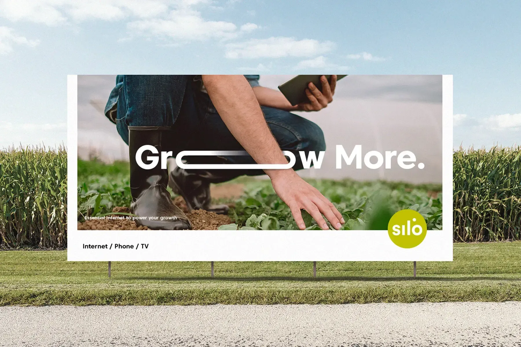 Silo roadside billboard by a cornfield reading Grow More, advertising internet, phone and TV